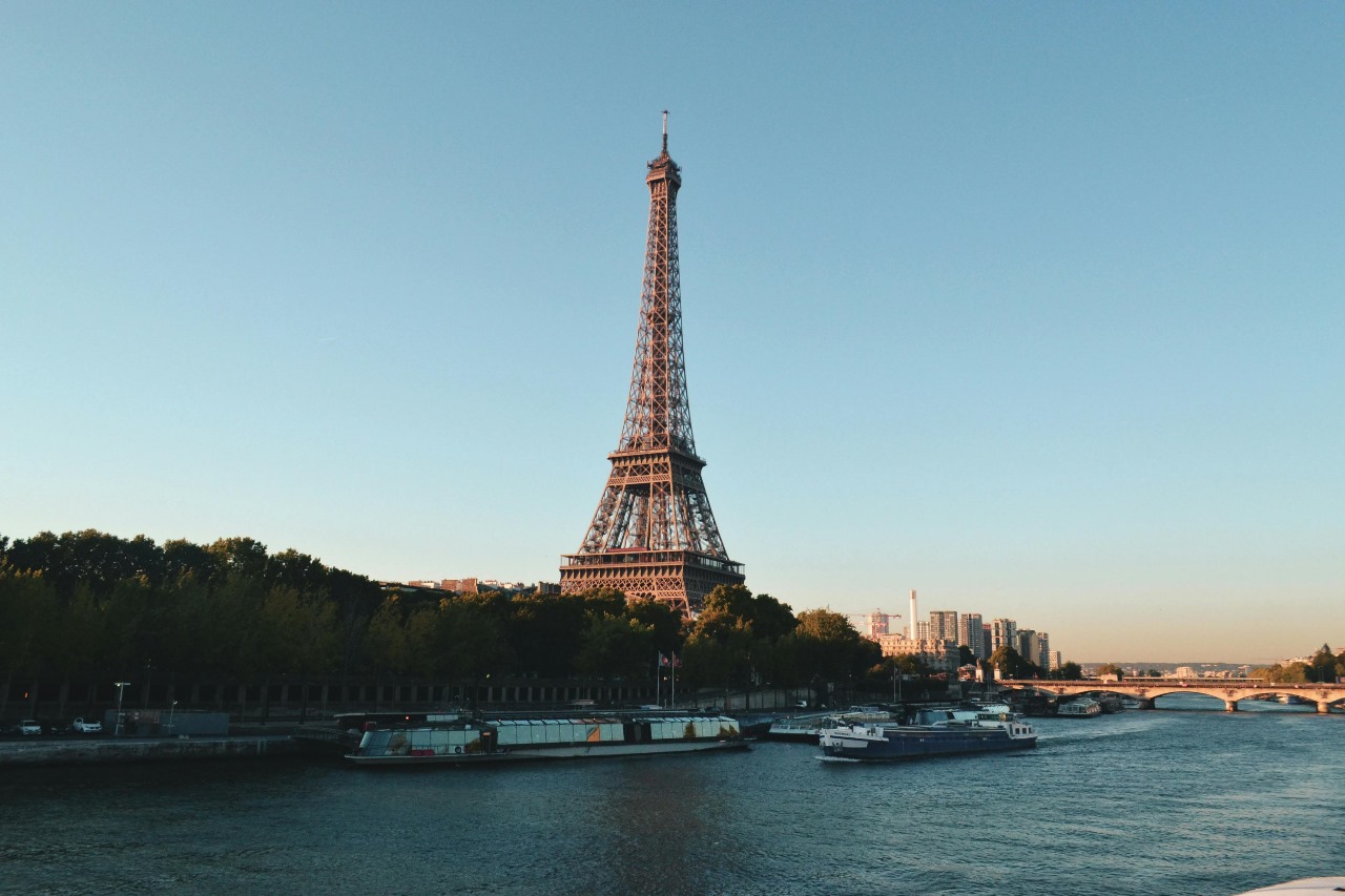 Iconic Eiffel Tower viewed from across the Seine River in Paris with boats on the water, representing France's cultural richness and prestigious academic institutions