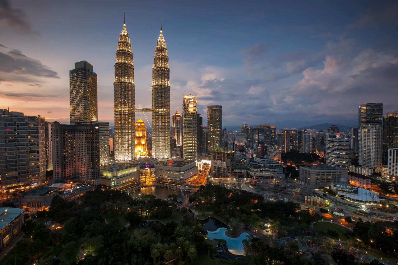 Kuala Lumpur's stunning skyline at dusk featuring the illuminated Petronas Twin Towers dominating the cityscape, showcasing Malaysia's modern development and affordable education options