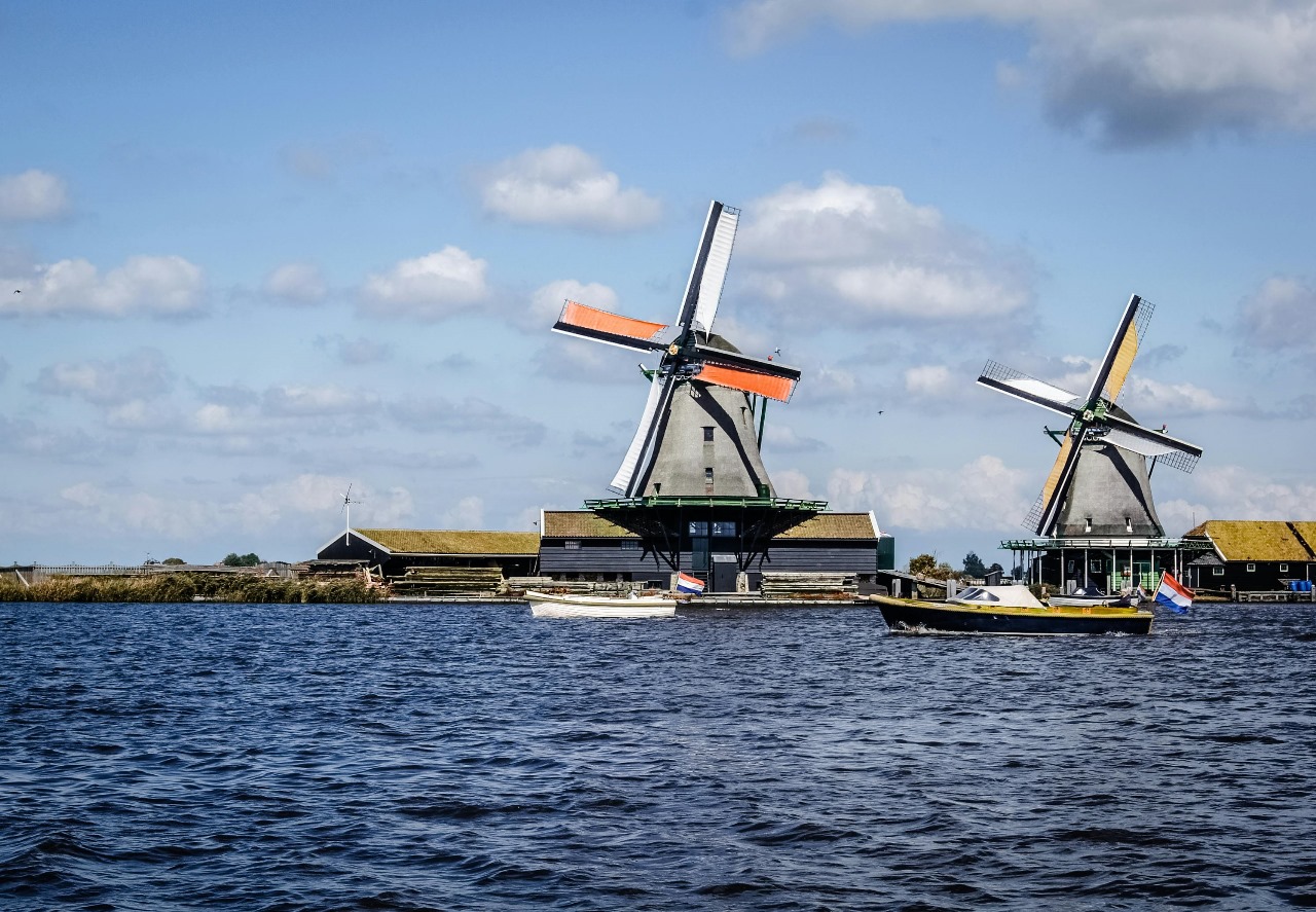 Classic Dutch windmills by the water with traditional architecture and boats, showcasing the Netherlands' iconic symbols of innovation, water management, and sustainable engineering